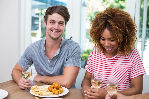 Jóvenes amigos con vino y comida en la mesa