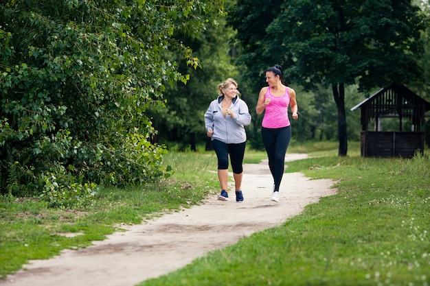 Jóvenes y ancianas corren cerca en verano parque al aire libre