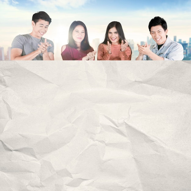 Jóvenes aplaudiendo con papel en blanco