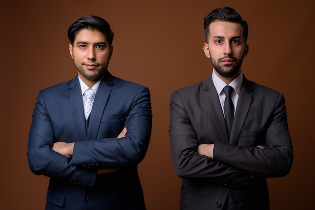 Jóvenes apuestos hermanos iraníes juntos contra la pared marrón