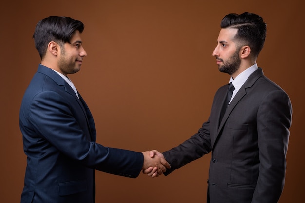 Jóvenes apuestos hermanos iraníes juntos contra la pared marrón