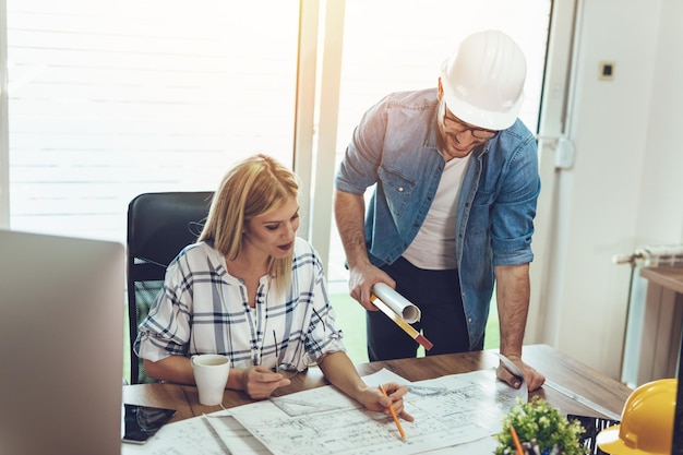 Jóvenes arquitectos preocupados hablando y analizando planos mientras trabajan en un nuevo proyecto en la oficina.