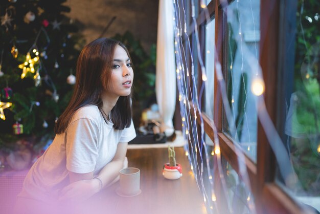 Las jóvenes asiáticas están felices y disfrutan de celebrar la víspera de Navidad en el café Fondo claro de la fiesta de Navidad que se muestra en el café