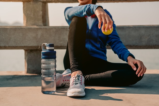 Jóvenes asiáticas sentadas a descansar después de hacer jogging por la mañana en la ciudad