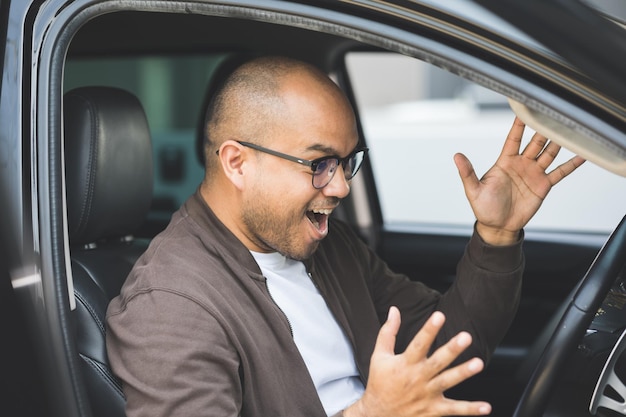 Jóvenes asiáticos de unos 30 años que consiguen un coche nuevo. Él muy feliz y emocionado.