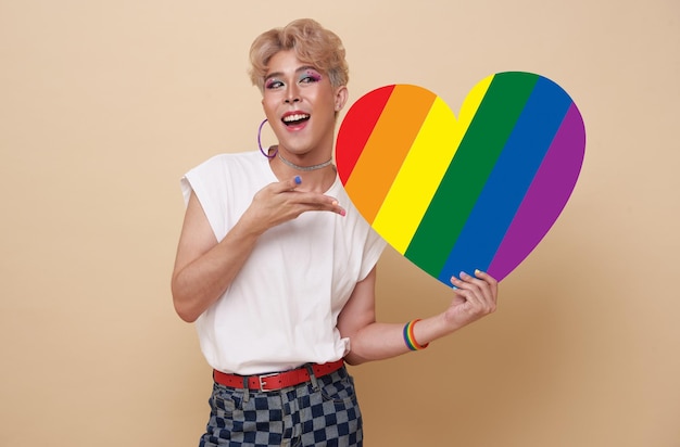 Jóvenes asiáticos transgénero LGBT que muestran el corazón del arco iris aislado sobre un fondo de color desnudo