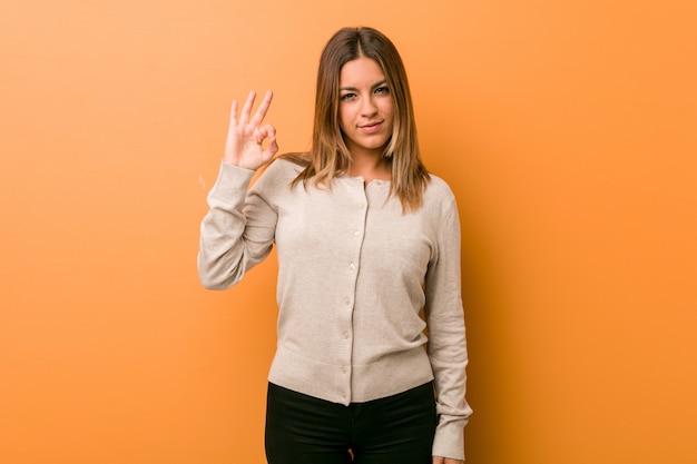 Jóvenes auténticos carismáticos personas reales mujer contra una pared alegre y confidente mostrando gesto bien.