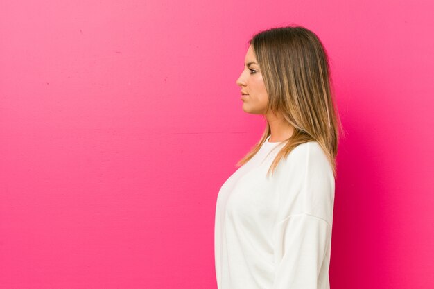 Foto jóvenes auténticos carismáticos personas reales mujer contra una pared mirando a la izquierda, de lado posan.