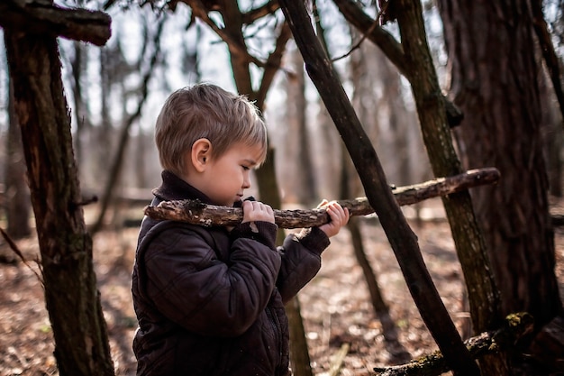 Jóvenes aventureros construyendo un hábitat de madera en el bosque salvaje durante la caminata social distante