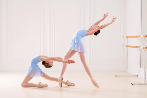 Jóvenes bailarinas ensayando en el estudio Fila de jóvenes bailarinas felices practicando en la barra de ballet se centran en la primera chica