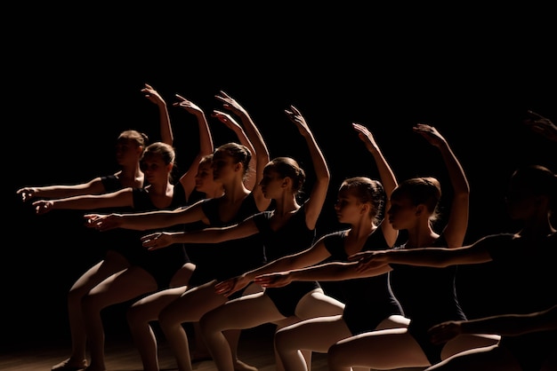 Jóvenes bailarinas practicando un baile coreografiado, todos lloviendo sus brazos al unísono elegante durante la práctica en una escuela de ballet.