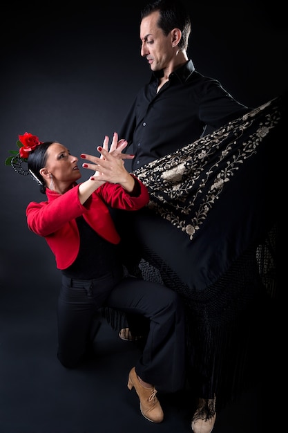 Jóvenes bailarines de flamenco en hermoso vestido sobre fondo negro.