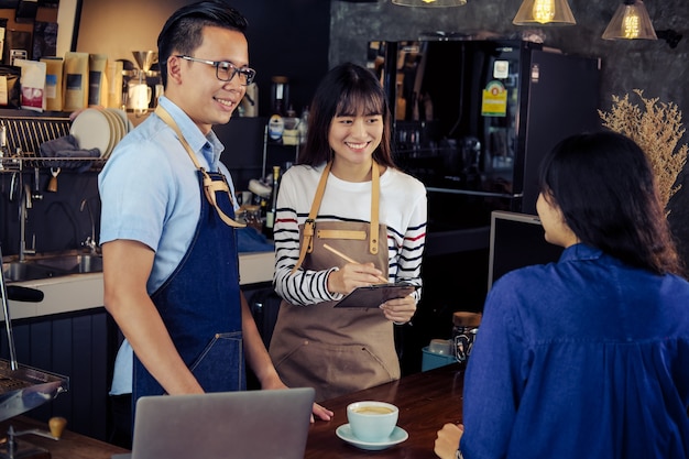 Jóvenes baristas pidiendo en barra de bar en café