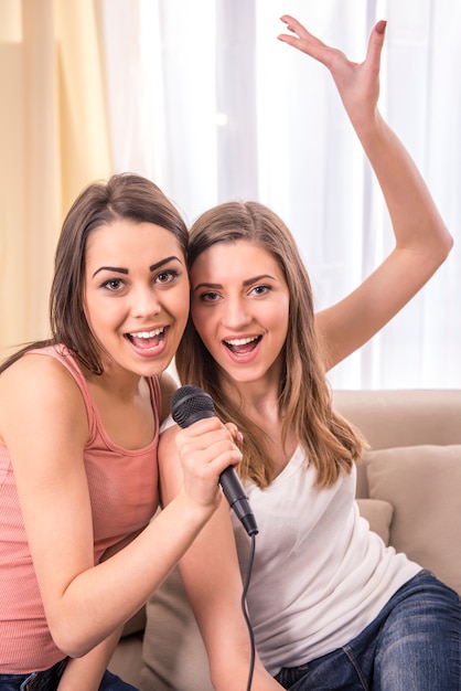 Las jóvenes bellas cantan una canción en casa.