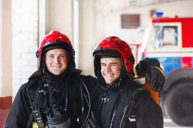 Foto jóvenes bomberos en el fondo de camiones de bomberos