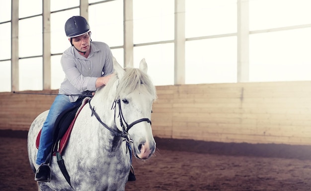 Jóvenes a caballo entrenando en una arena de madera