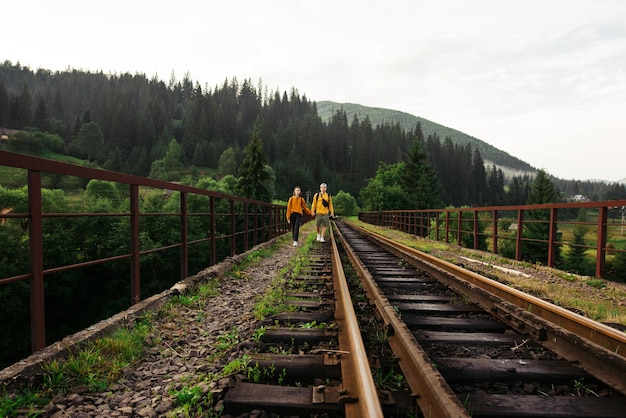 jóvenes caminando tomados de la mano en la vía férrea en un viaducto en las montañas