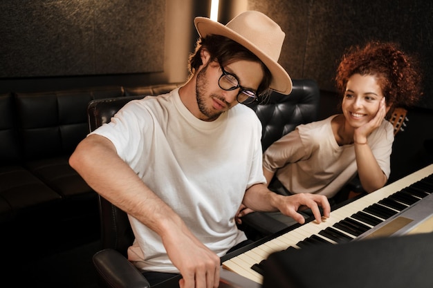 Jóvenes cantantes con estilo creando música en un moderno estudio de grabación de sonido. Atractivos músicos trabajando en estudio de grabación.