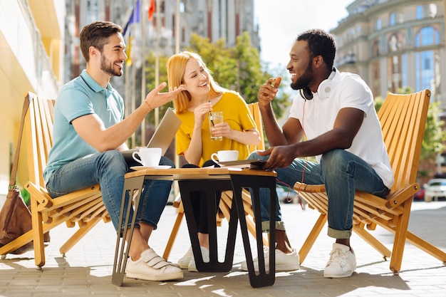 Jóvenes carismáticos discutiendo y divirtiéndose en el café