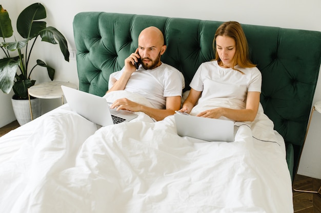 Jóvenes en casa o una hermosa pareja milenaria en el hotel que utilizan conexión a Internet y dispositivos tecnológicos como computadora portátil