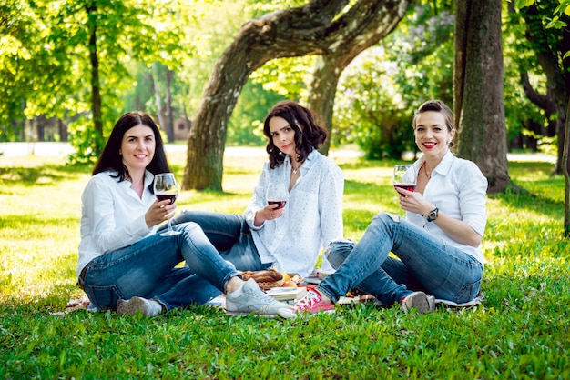 Jóvenes chicas guapas con copa de vino tinto en el parque