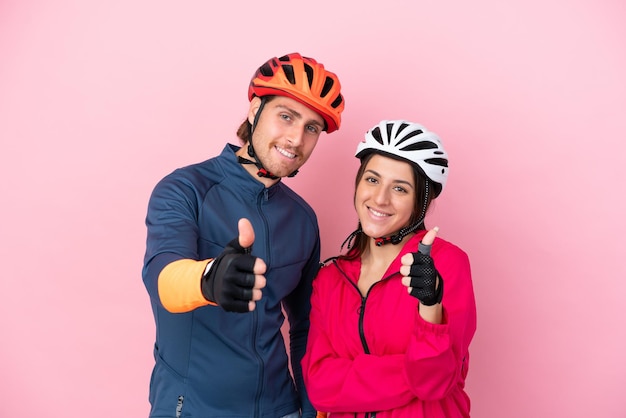 Jóvenes ciclistas caucásicos aislados de fondo rosa dando un gesto de aprobación porque algo bueno ha sucedido