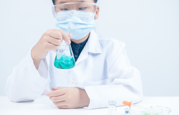 Jóvenes científicos agitando químico líquido azul en matraz Erlenmeyer aislado sobre fondo blanco. Laboratorio de ciencias y concepto de educación.