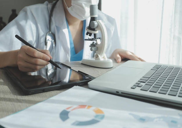 Jóvenes científicos que realizan investigaciones en un laboratorio médico, un investigador en primer plano está usando un microscopio