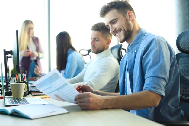 Jóvenes colegas modernos en ropa casual elegante trabajando juntos mientras pasan tiempo en la oficina creativa.