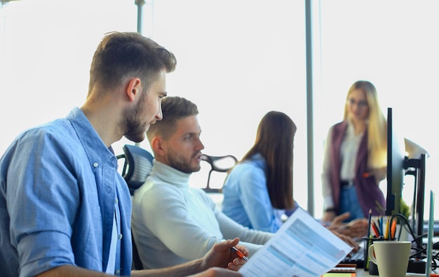 Jóvenes colegas modernos con ropa informal inteligente trabajando juntos mientras pasan tiempo en la oficina creativa