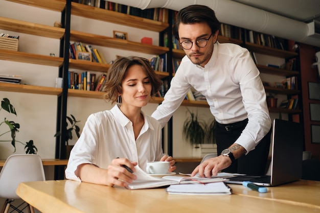 Jóvenes colegas de negocios atractivos trabajando felizmente en un nuevo proyecto juntos en una oficina moderna