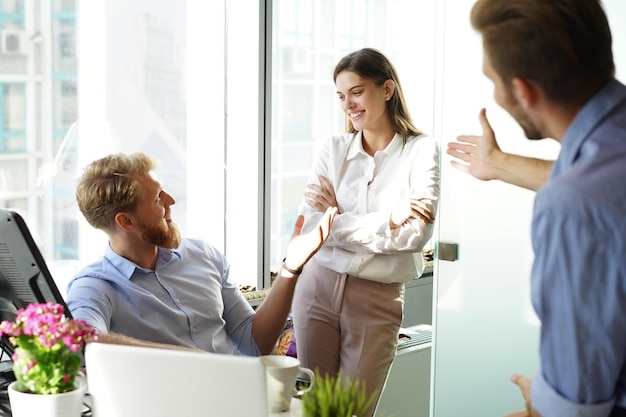 Jóvenes colegas con ropa informal inteligente trabajando mientras pasan tiempo en la oficina.