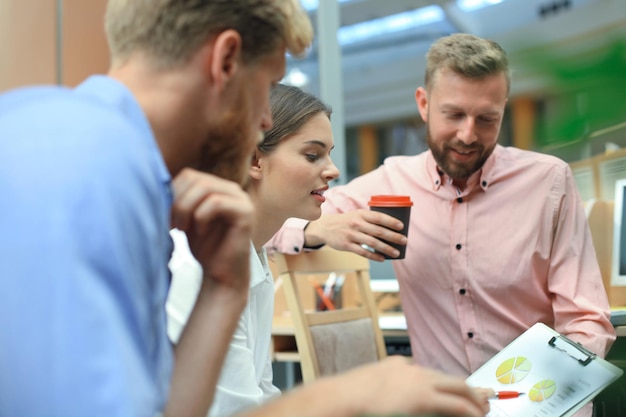 Jóvenes colegas con ropa informal inteligente trabajando mientras pasan tiempo en la oficina.