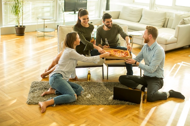 Jóvenes comiendo pizza y bebiendo sidra en el interior moderno