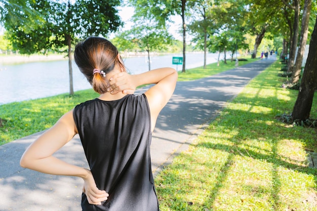 Foto jóvenes corredoras hacen ejercicio en el parque con fuertes dolores de espalda y cuello por correr