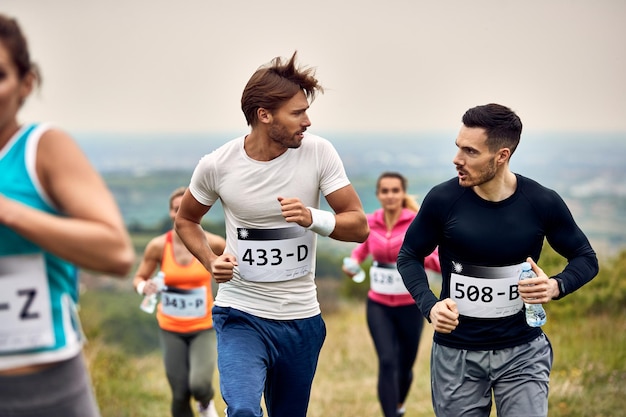 Jóvenes corredores masculinos comunicándose mientras participan en una carrera en la naturaleza