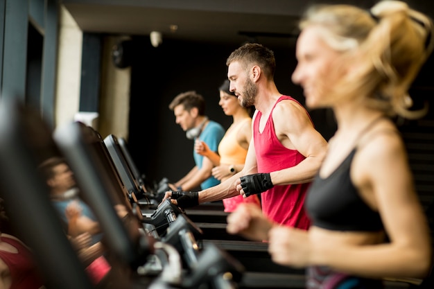 Jóvenes corriendo en cintas de correr en un moderno gimnasio