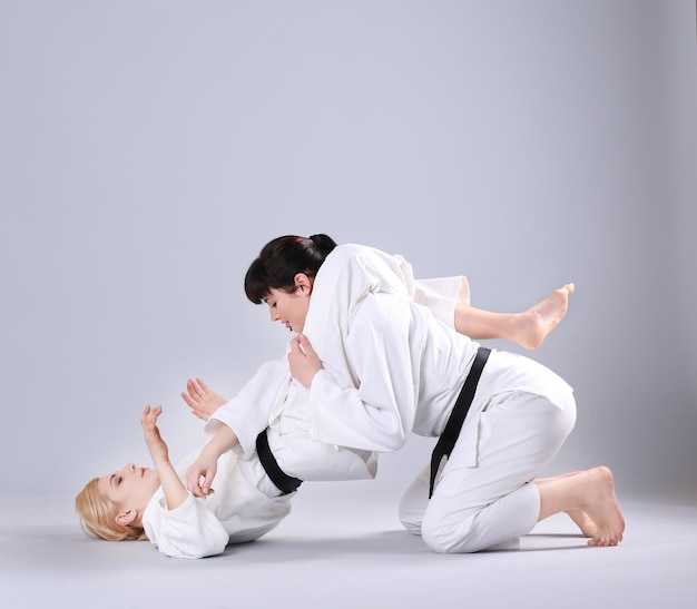 Jóvenes deportistas practicando artes marciales sobre fondo claro