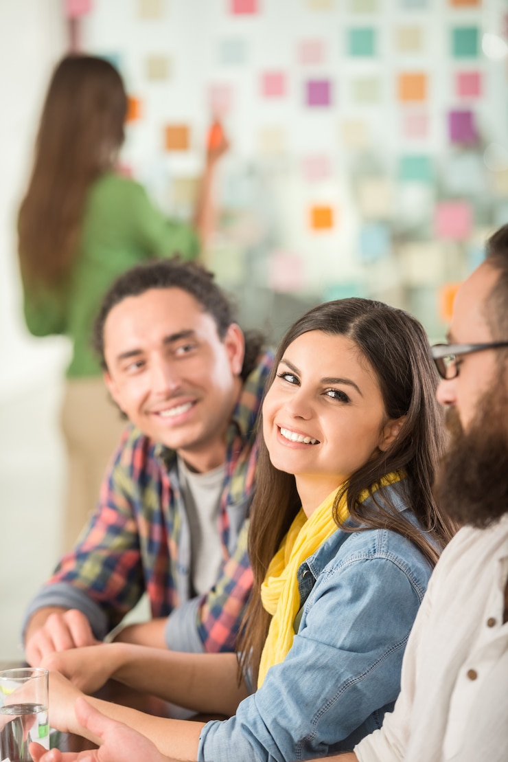 Foto jóvenes diseñadores de interiores sentados en la oficina e intercambiando ideas.