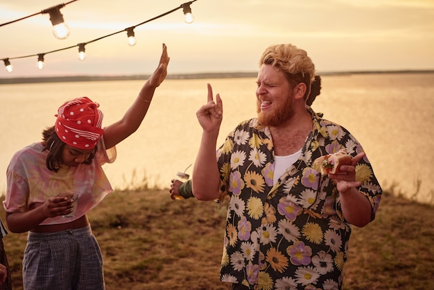 Jóvenes divirtiéndose y bailando juntos al aire libre en la playa