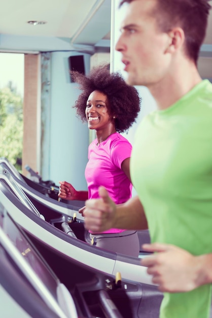 jóvenes ejerciendo un cardio en cinta rodante corriendo lomo en un gimnasio moderno