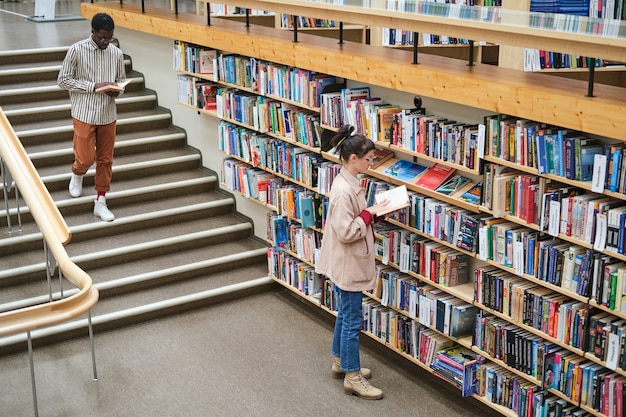 Jóvenes eligiendo libros y leyéndolos en la biblioteca.
