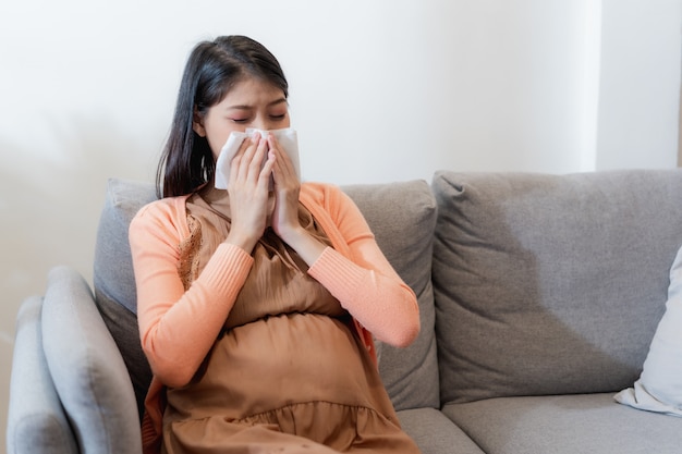 Las jóvenes embarazadas asiáticas sufren de gripe y estornudos, secreción nasal, nariz tapada