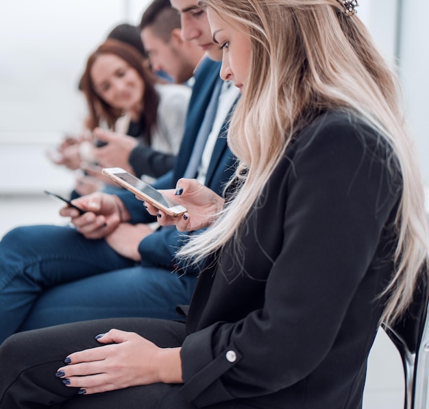 Jóvenes empleados mirando las pantallas de sus teléfonos inteligentes