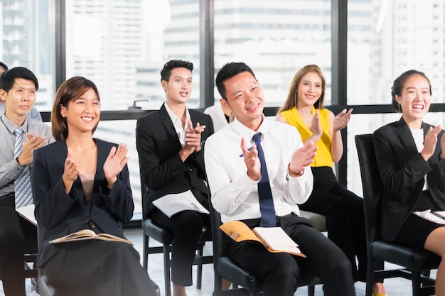 Jóvenes empresarios aplaudiendo durante la reunión en el cargo por su éxito en el trabajo empresarial