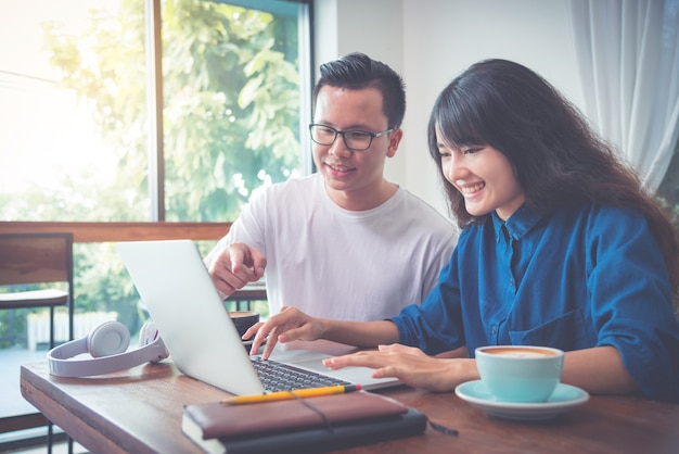 Jóvenes empresarios asiáticos que trabajan con la computadora portátil en la cafetería