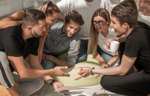 Jóvenes empresarios discutiendo documentos comerciales en una reunión informal el concepto de trabajo en equipo