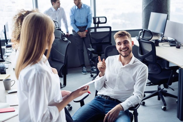 Los jóvenes empresarios exitosos están hablando y sonriendo durante la pausa para el café en la oficina.