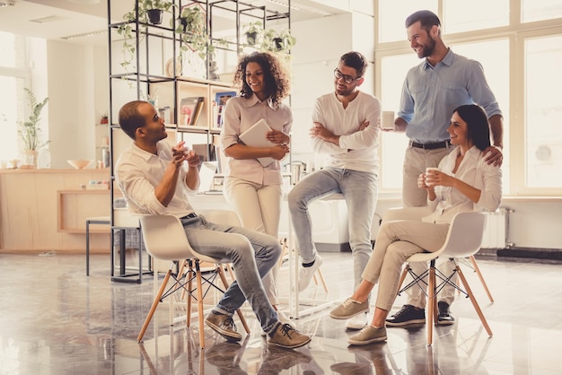 Jóvenes empresarios exitosos están hablando y sonriendo durante la pausa para el café