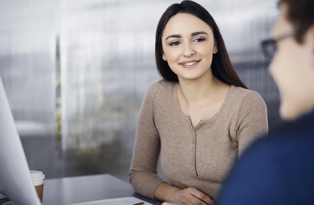 Los jóvenes empresarios hablan entre sí mientras están sentados en el escritorio de una oficina moderna. Concepto de éxito empresarial.